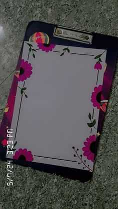 a clipboard with pink flowers on it sitting on the floor next to a mouse