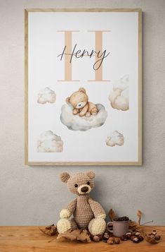 a teddy bear sitting on top of a wooden table next to a poster with the letter h