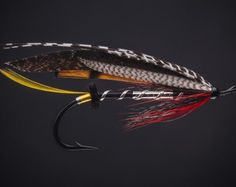 a black and yellow fishing lure with red, orange, and white flies on it