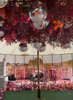 disco balls hanging from the ceiling in front of a stage with flowers and other decorations