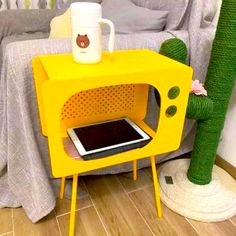 a yellow microwave oven sitting on top of a wooden table next to a cactus plant