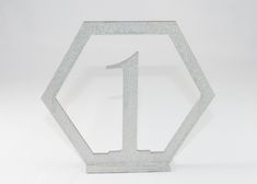 the number one sign is made out of silver glitter and sits on a white surface