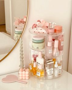 a white counter top with various containers and bottles on it next to a mirror that has a pink spoon in front of it