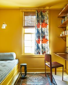 a bedroom with yellow walls and a bed in the corner, next to a window