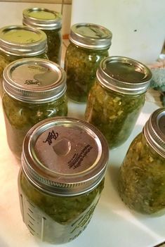 several jars filled with pickles sitting on top of a counter