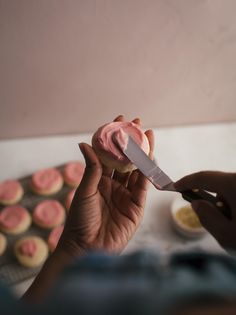 a person holding a knife in front of some cupcakes