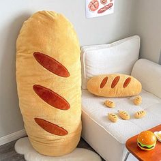 a large stuffed hot dog sitting on top of a white couch next to a table