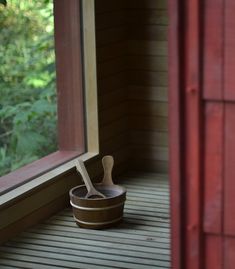 a wooden spoon sitting in a bowl on top of a porch next to a window