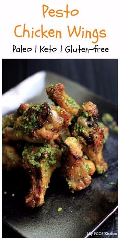 chicken wings covered in pesto and parsley on a black plate with a fork