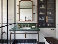 a bathroom with green marble counter top and white tile walls, along with a wooden cabinet