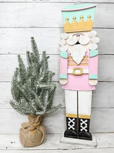 a wooden nutcracker standing next to a potted plant on a white wood background