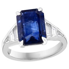 A stunning well-crafted engagement ring showcasing a 5.11-carat emerald-cut Blue Sapphire. Flanking the center diamond are perfectly matched graduating step-cut diamonds, channel set in a polished platinum mounting. 6 Accent diamonds weigh 0.68 carats total. Handcrafted in our New York City workshop. Style available in different price ranges. Prices are based on your selection. Please contact us for more information. Sapphire And Diamond Engagement Ring, Jewelry Rings Engagement, Emerald Cut, Diamond Engagement Ring, Ring Verlobung, Blue Sapphire, Diamond Engagement, Diamond Engagement Rings, Diamond Cuts