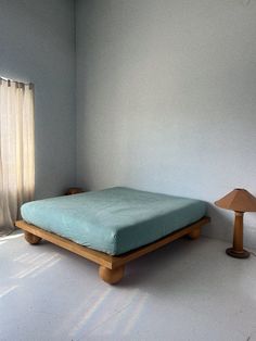 a bed sitting in the middle of a room next to a lamp and window with curtains