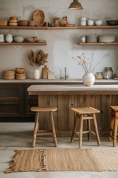 two stools sit in front of a kitchen island with wooden shelves and open shelving