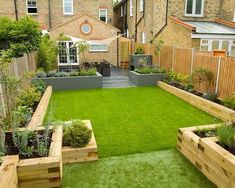 a small garden with grass and wooden planters in the back yard, surrounded by brick buildings