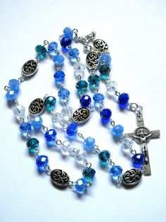 This mixed blue Lutheran rosary is made with AB faceted, transparent, 8x6 mm glass rondelles. The colors include light blue, dark cyan, cornflower blue. clear, and dark blue. The Sunday beads are 12mm, zinc based, pewter ovals, while the crucifix is Italian made, oxidized silver. I hand turned and linked the silver-plated wires. It is made in the Longworth Lenten pattern of six sets of seven beads. It measures about 23 inches around and has a 5-inch cross drop. This rosary will be slipped into a velvet bag and shipped in a bubble mailer. Blue Rosary With 8mm Beads For Healing, Blue Rosary With Round Beads For Healing, Blue Rosary Bracelet For Jewelry Making, Spiritual Blue Rosary With Round Beads, Spiritual Blue Rosary With 108 Beads, Blue 108 Beads Spiritual Rosary, Blue Rosary For Healing, Blue Healing Rosary, Blue Spiritual Rosary Bracelet With 8mm Beads