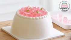 a white cake with pink flowers in it on a wooden table next to other cakes