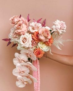 a woman holding a bouquet of flowers in her hand with pink and peach colors on it