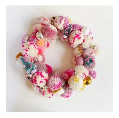 a knitted wreath with pom - poms and bells hanging from the front