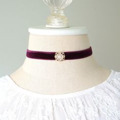 This elegant choker necklace is handmade with a soft velvet ribbon in a rich eggplant purple hue. It features a sparkling gold tone rhinestone and pearl center jewel. A one-of-a-kind gift for a friend who loves unique jewelry! Also available with a teal blue velvet ribbon, sold separately in the Rosy Posy Designs shop.  * Length ~ 12 inches + 3 inch extender (fits a 12-15 inch neck size)  * Band ~ 1/2 inch wide velvet band * Fastens with lobster clasp * Ships in a pretty gift box Discover more o Purple Choker Necklace For Gift, Elegant Burgundy Jewelry For Party, Elegant Burgundy Party Jewelry, Adjustable Purple Choker For Party, Adjustable Burgundy Jewelry For Party, Elegant Purple Choker Jewelry, Elegant Purple Wedding Choker, Jewel Choker, Blue Velvet Ribbon