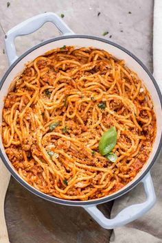 a large pot filled with spaghetti on top of a wooden table