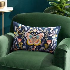 a green chair with a blue pillow on it in front of a potted plant