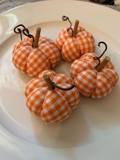 four orange pumpkins sitting on top of a white plate