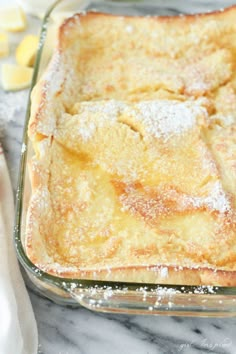 a casserole dish with powdered sugar on top, sitting on a marble counter