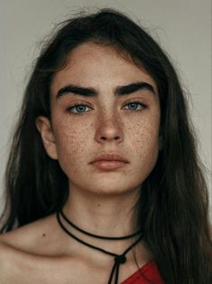 a woman with freckles on her face wearing a black choker and necklace