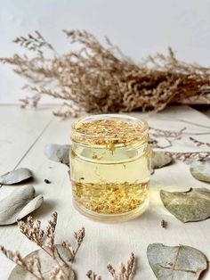 a jar filled with yellow flowers sitting on top of a white table next to dried plants