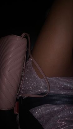 a woman's legs and handbag are shown in the dark, with glitter on them