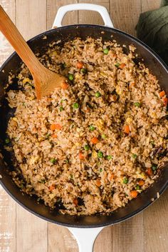 a pan filled with rice and vegetables on top of a wooden table