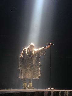 a man standing on top of a stage with his arms outstretched in front of him