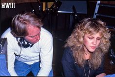 a man and woman sitting next to each other in front of a microphone with headphones on