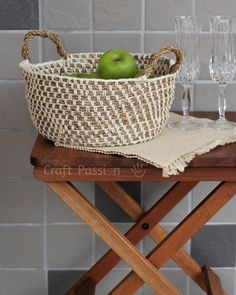 an apple sits in a woven basket next to two wine glasses