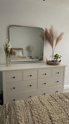 a bedroom with a bed, dresser and mirror on the wall next to each other