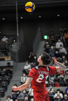 a man in red shirt jumping up to hit a volleyball