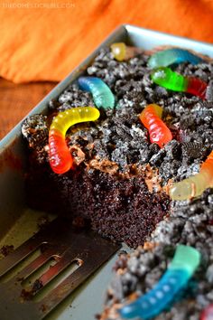 a piece of chocolate cake with gummy bears on it and a fork in the foreground