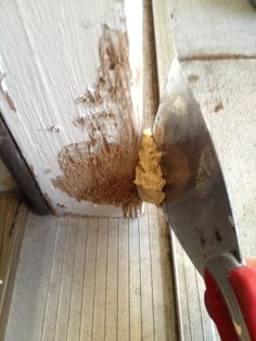 a person is holding a knife in their left hand and removing wood from the floor