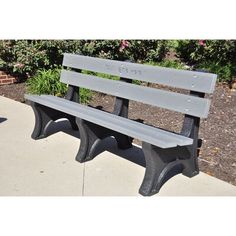 a park bench sitting on top of a sidewalk next to bushes and flowers in the background