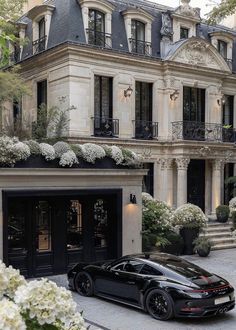 a black sports car is parked in front of a large building with many windows and balconies