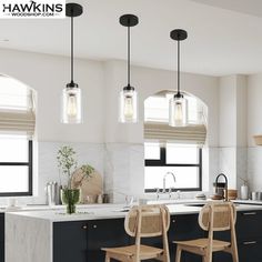 three lights hanging over a kitchen island in a room with black cabinets and white counter tops