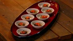 a tray filled with small white bowls on top of a wooden table