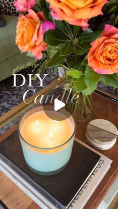 a vase filled with orange roses sitting on top of a table next to a candle