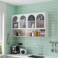 a kitchen with green tiles and white cabinets