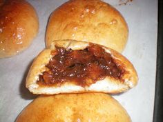 three buns with meat in them sitting on a baking sheet next to each other