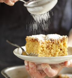 a person is sprinkling sugar on a piece of cake