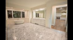 a large bathroom with marble flooring and white walls, along with an oval bathtub