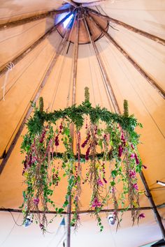 the inside of a yurt with flowers and plants hanging from it's ceiling