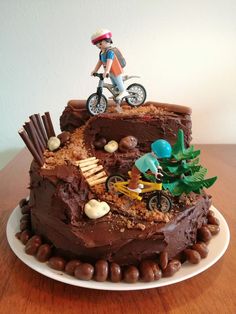 a birthday cake with a man riding a bike on top of it and rocks around the base